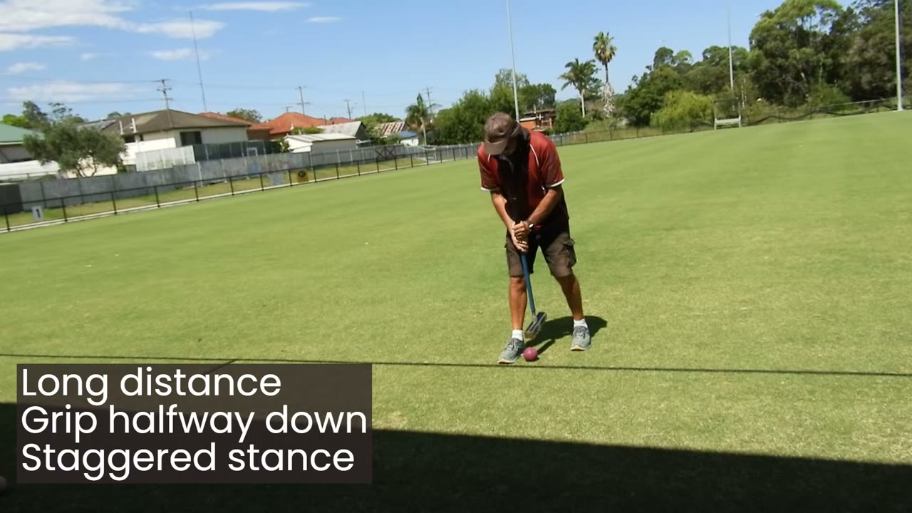 Player in a staggered stance addressing a ball at distance from a hoop, caption: 'Long distance: Grip halfway down. Staggered stance.'