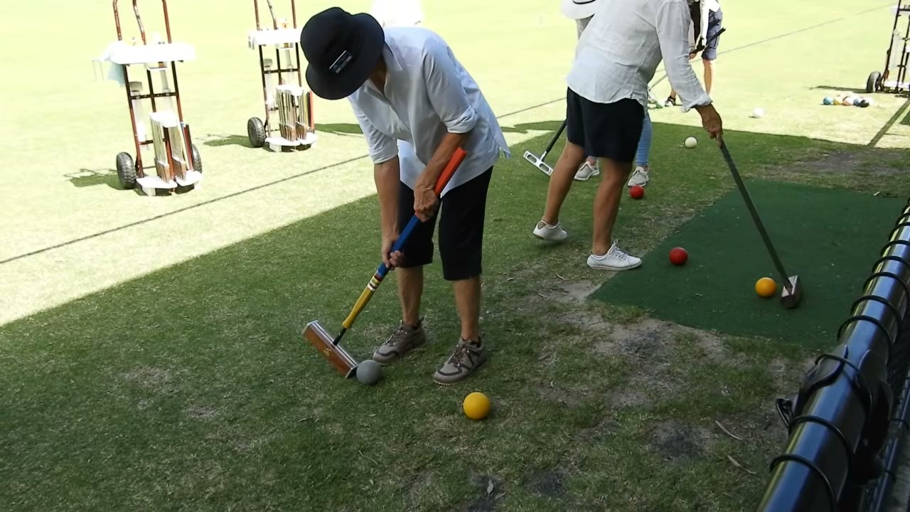Several students lined up at portable mats with mallets and balls, practising jump shots in sequence.